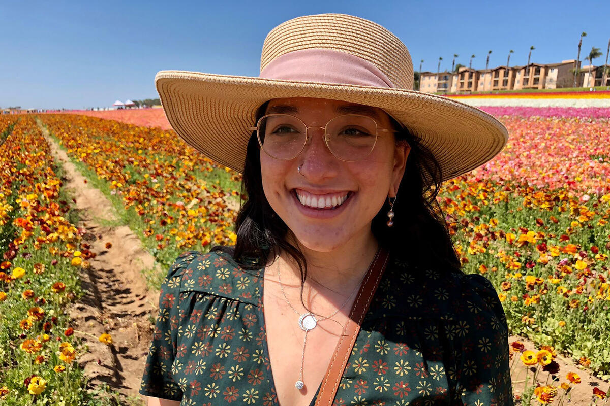 A woman in a sunhat stands in a field of flowers
